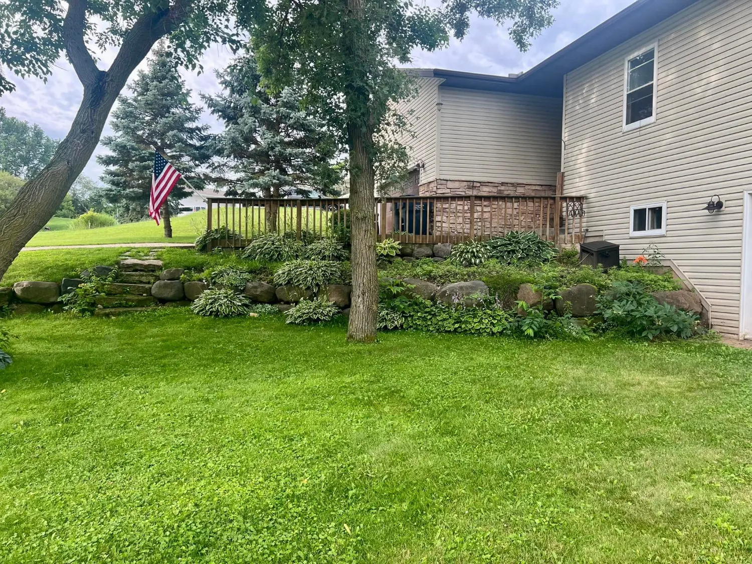 The original boulder wall and overgrown planting bed along the side of the house, before the rebuild