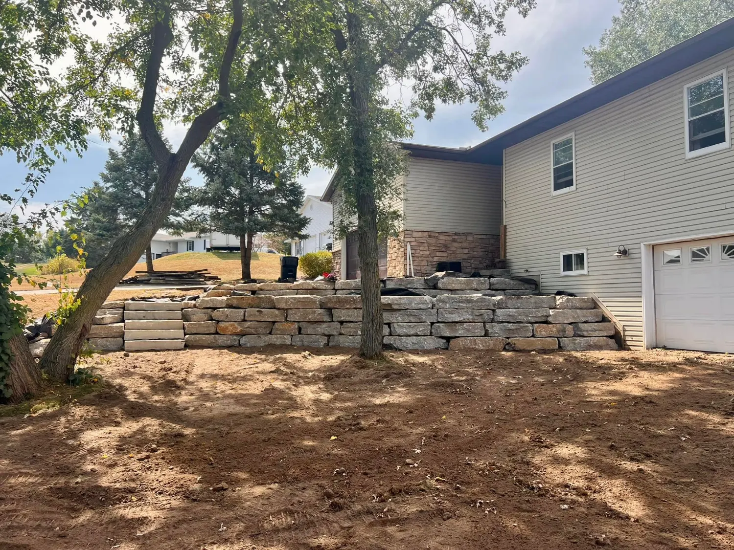 The finished limestone outcropping wall holding the grade beside the garage