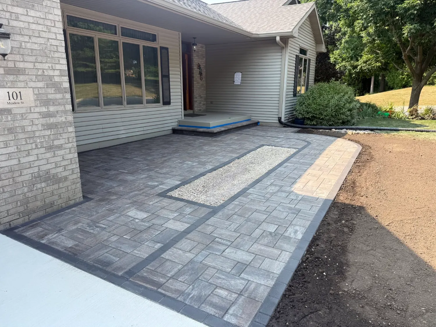 Grey paver entry courtyard with a charcoal soldier border and a gravel planting inlay