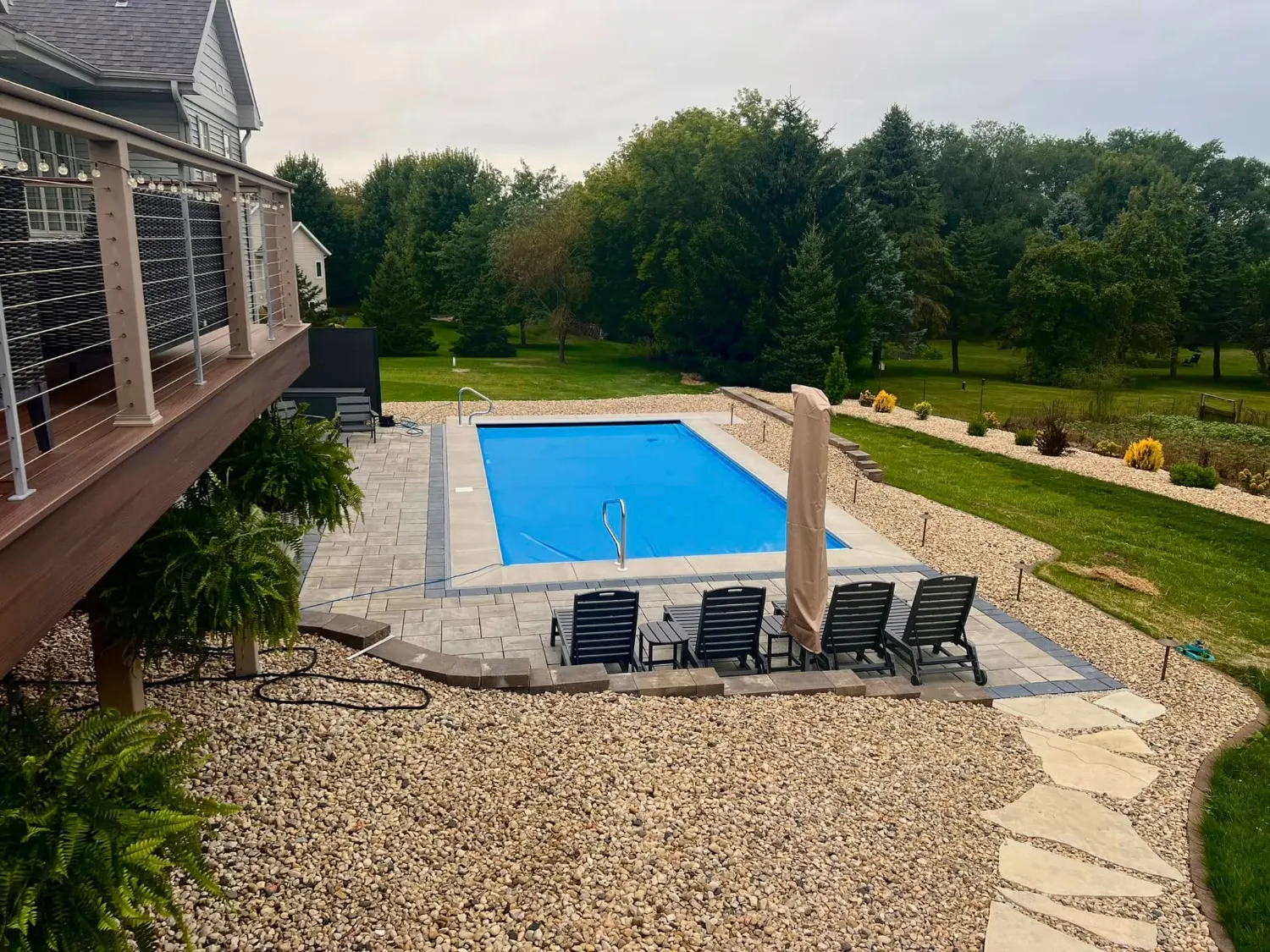 Paver pool surround with a stepped border, lounge chairs and a flagstone stepper path